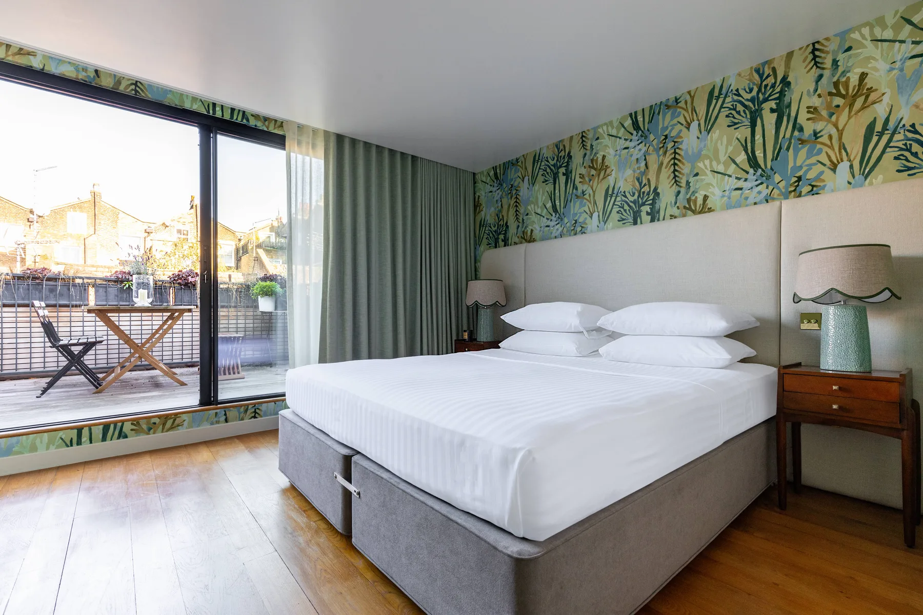 A bedroom with a large bed, bedside tables, and sliding glass doors to a balcony.