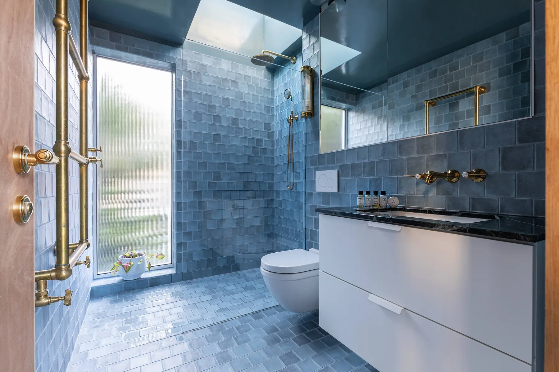 A tiled bathroom with a glass shower, toilet, and vanity.