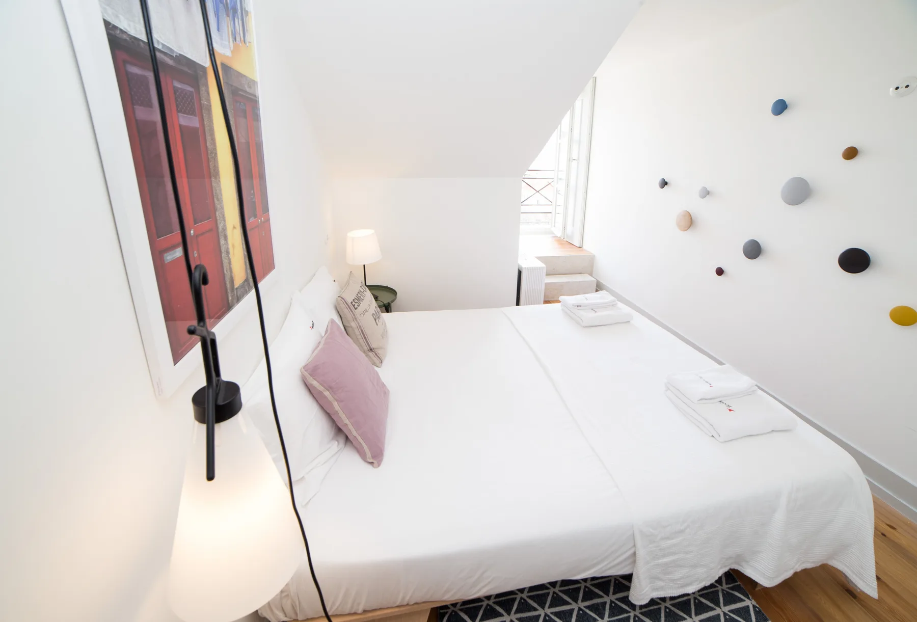 Un dormitorio luminoso con una cama bien hecha y arte colorido en la pared.