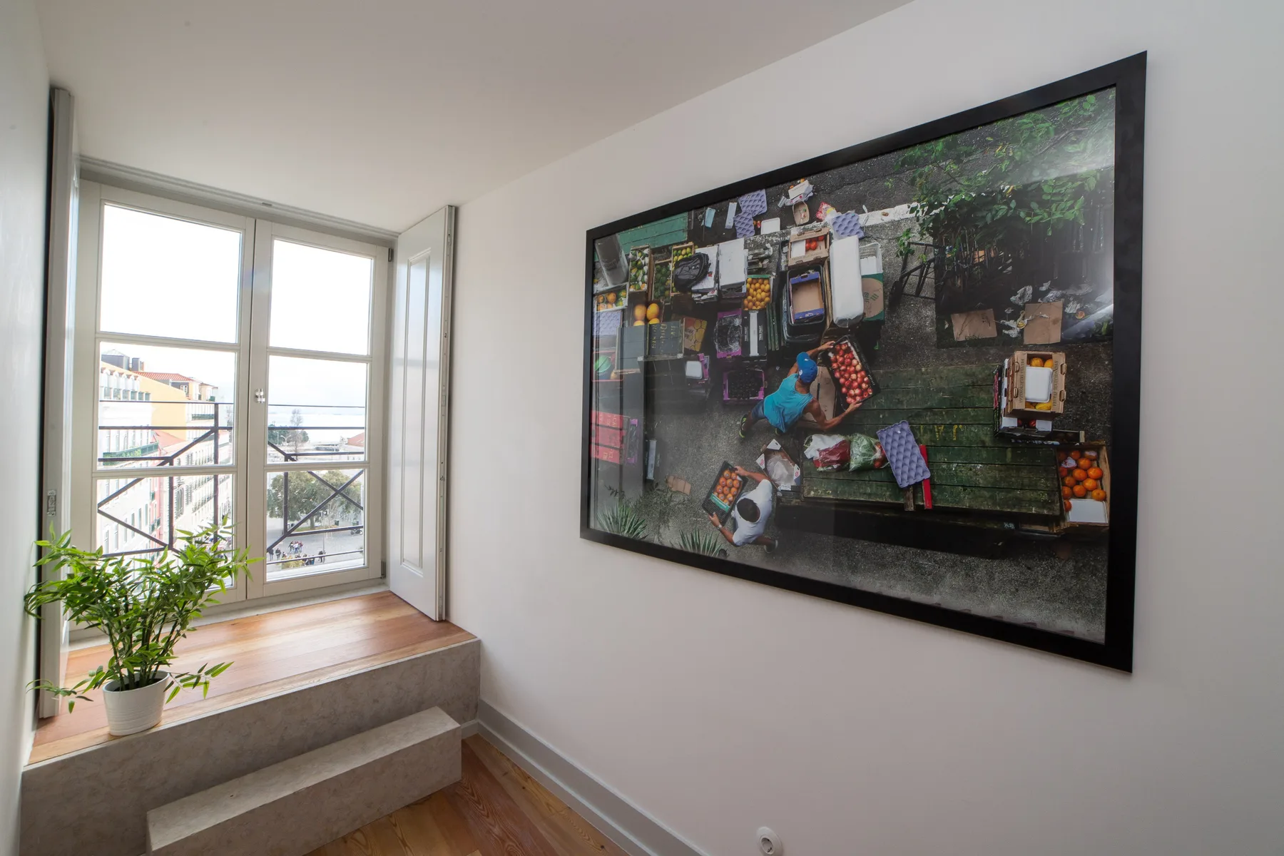 A bright interior shows a large framed picture beside a window and steps.