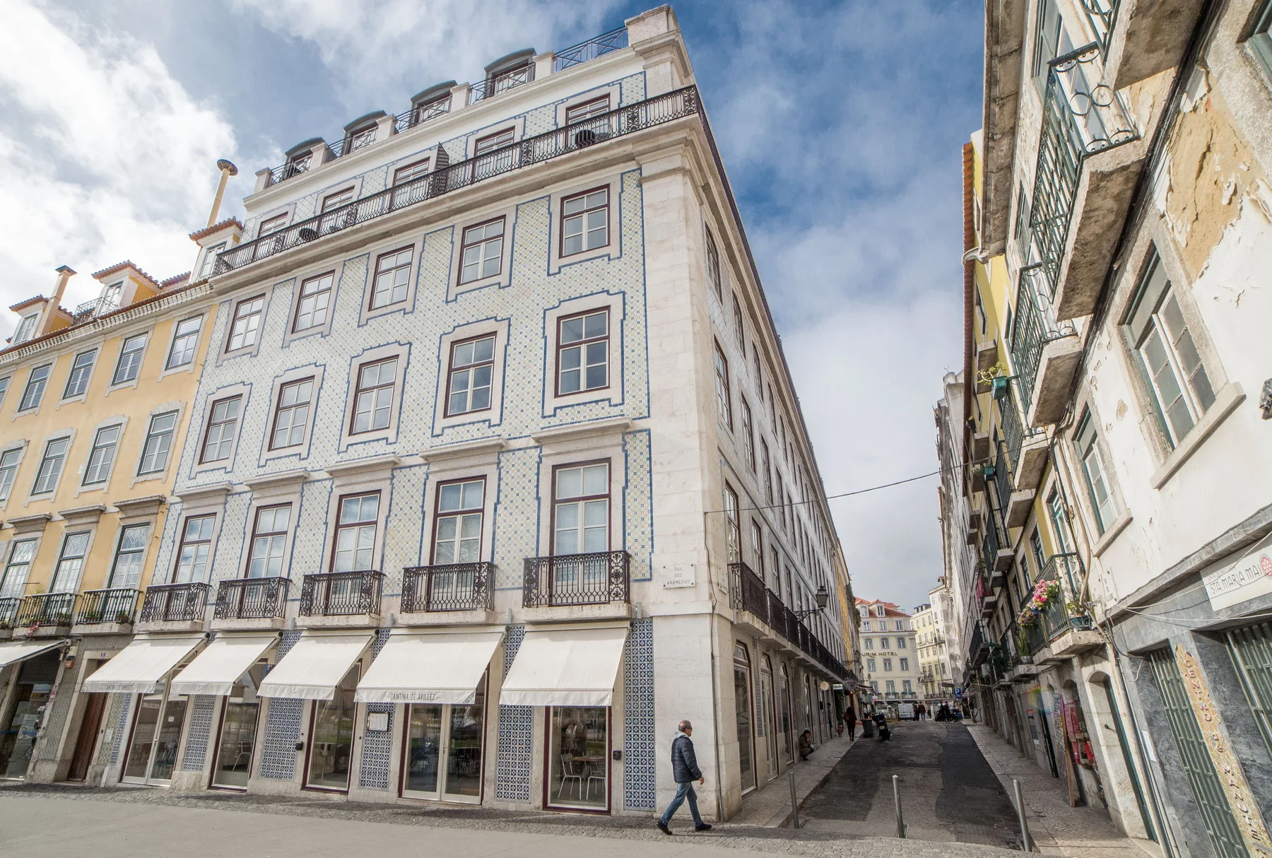 A narrow street runs between tall historic buildings with shops at street level.