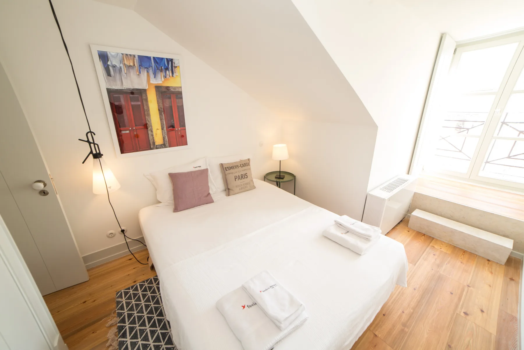Un dormitorio luminoso con una cama bien hecha bajo un techo inclinado.