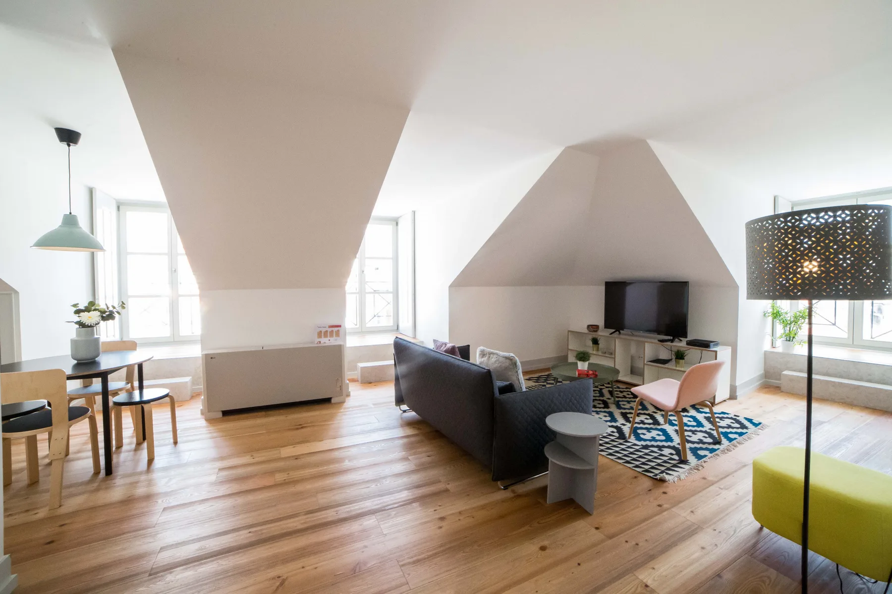 A bright living room with a dining table, seating, and a television.