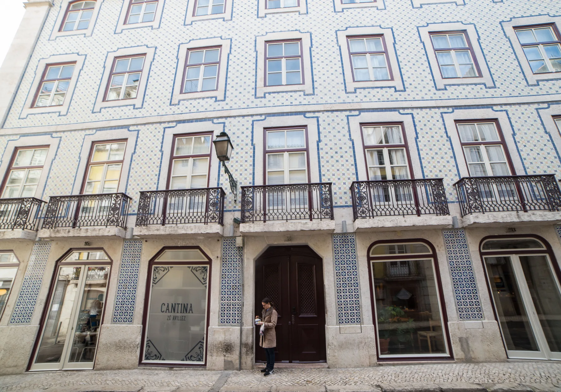 A tiled building facade with rows of windows, balconies, and a central doorway.