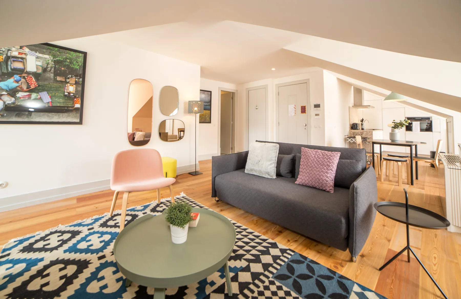 A living room with a dark sofa, patterned rug, and adjoining dining area.