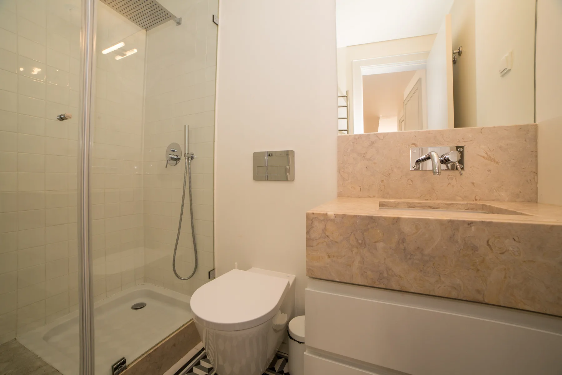 A bright bathroom with a glass shower and a wide sink counter.