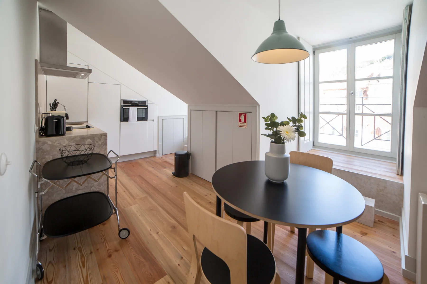 A bright kitchen and dining area with a round table beside large windows.