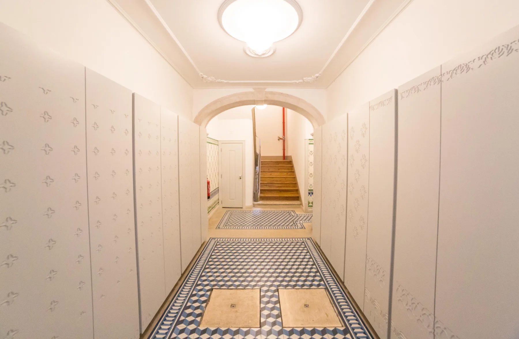 A patterned tiled hallway leads through an archway to a staircase.