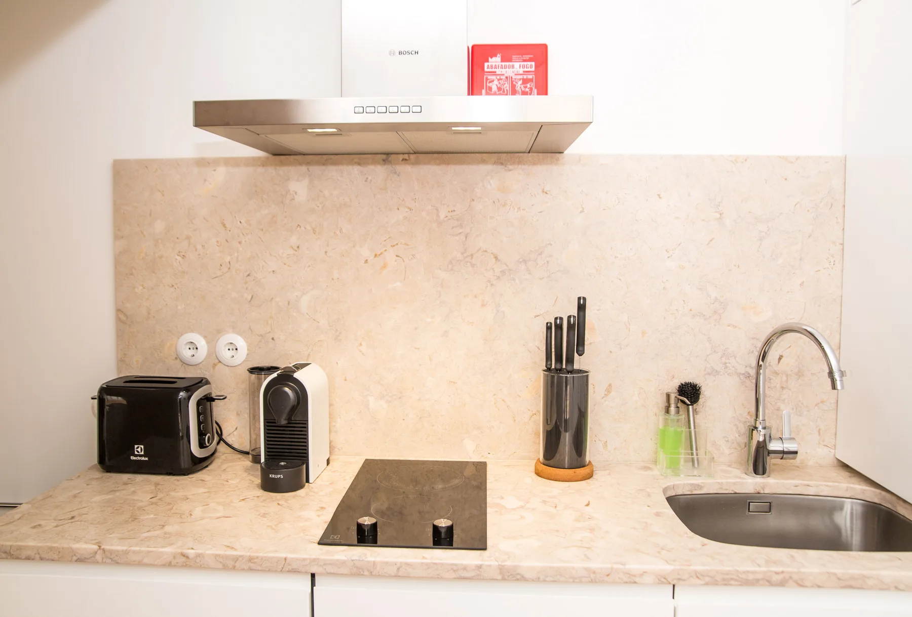 A bright kitchen counter with a cooktop, small appliances, and a sink.