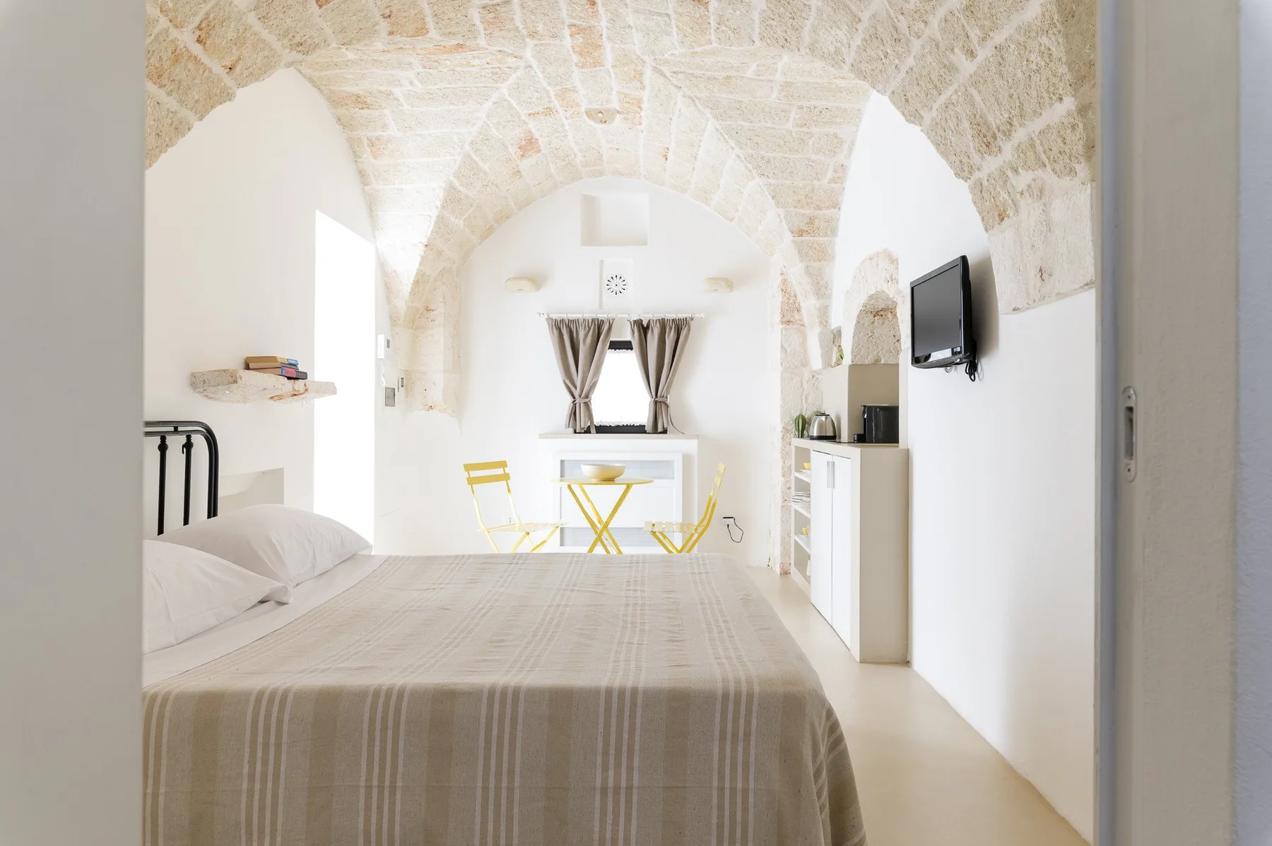 Un dormitorio luminoso con una cama bajo un techo abovedado de piedra.