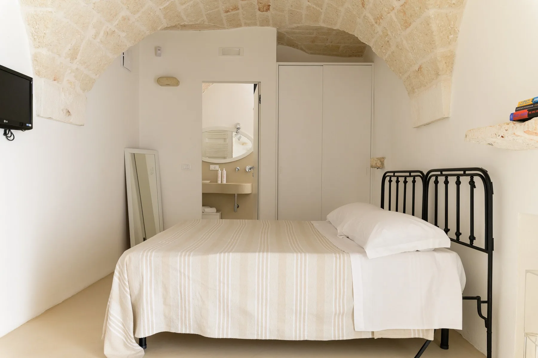 Un dormitorio con una cama bajo un techo curvo de piedra.