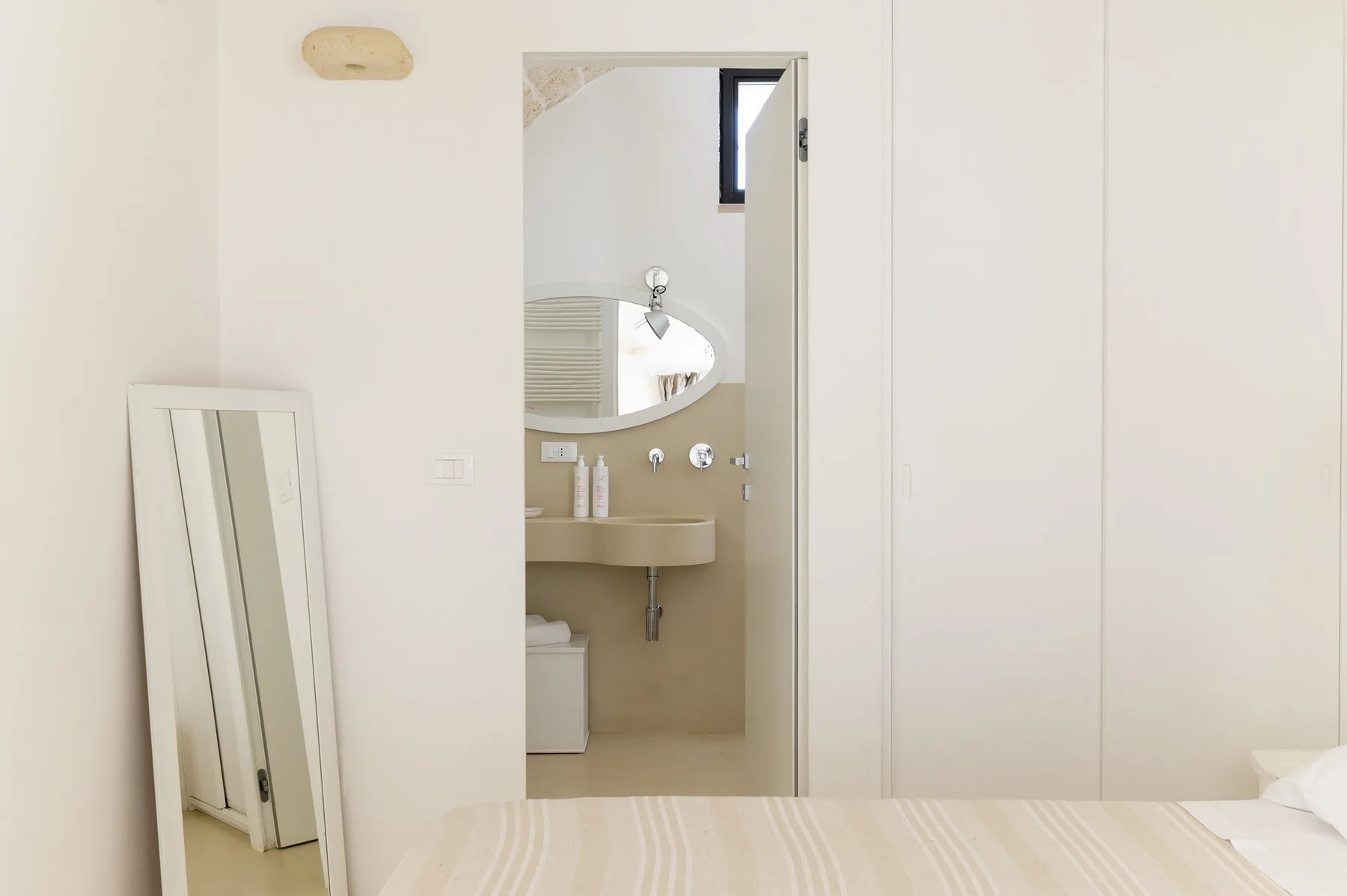 Un dormitorio con una cama en primer plano y un baño visible a través de la puerta.