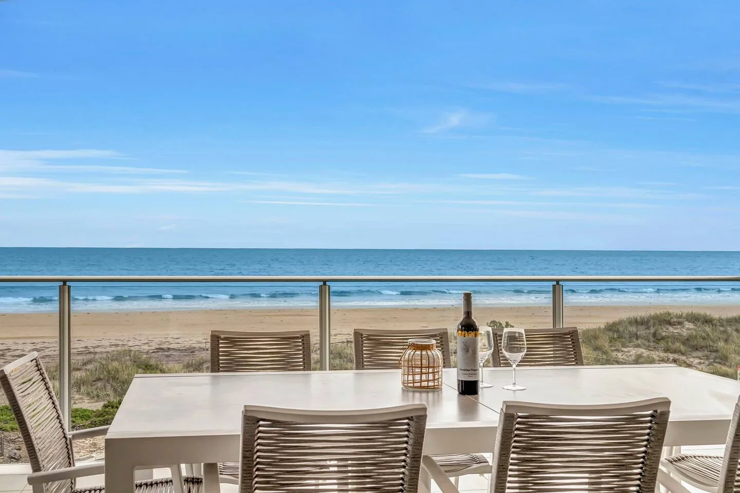 Una zona de comedor al aire libre da a una playa de arena y al océano.