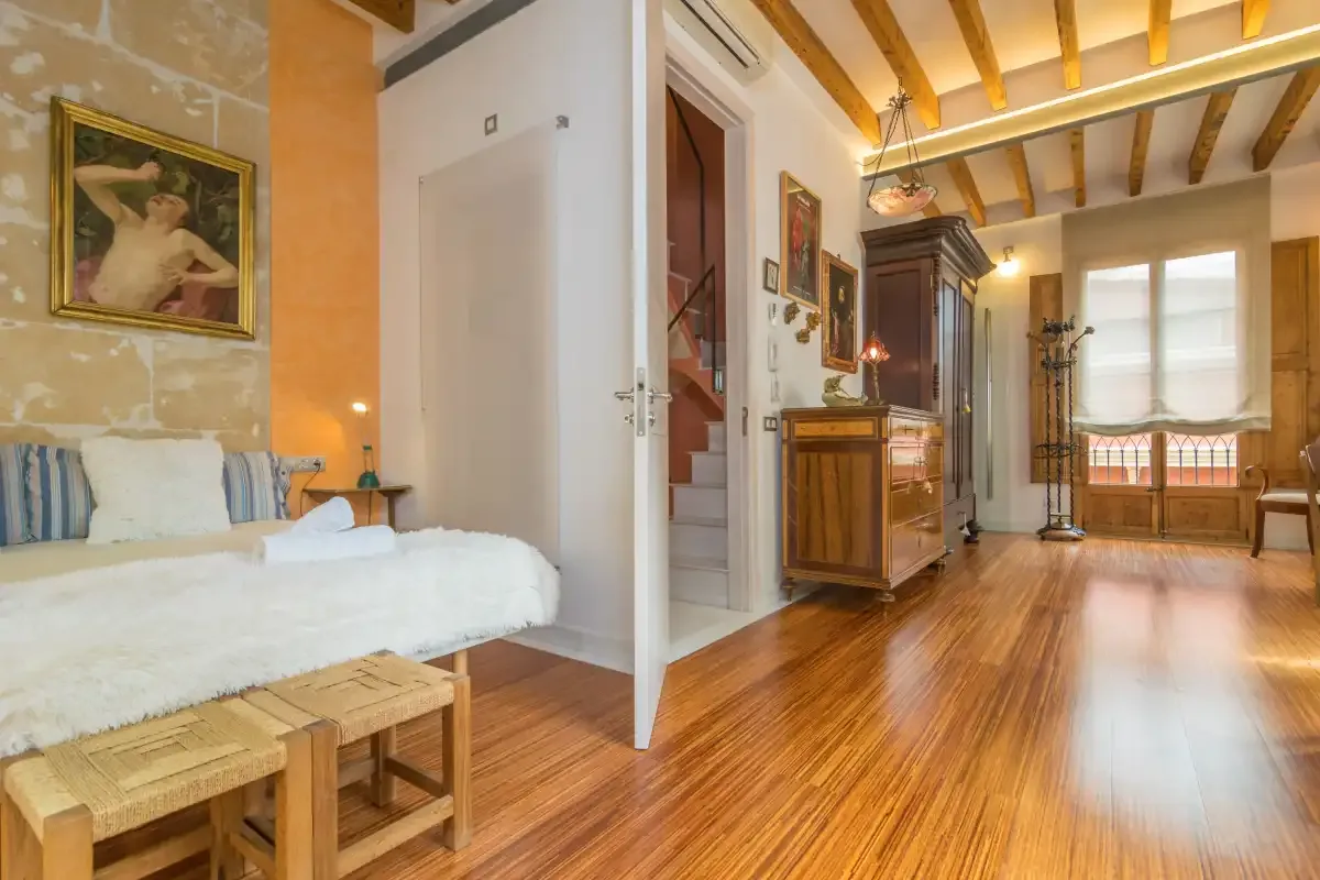 A bedroom opens onto a sitting area with wooden ceiling beams and polished floors.