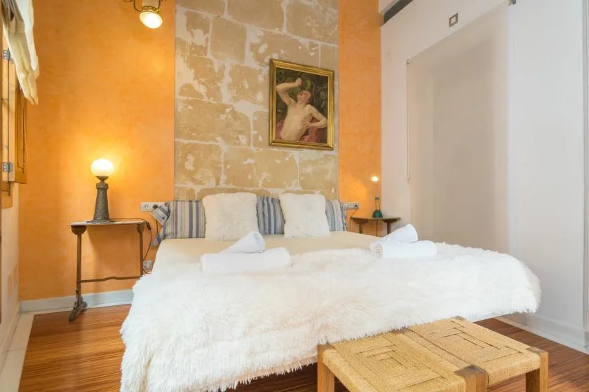 A bedroom with a white bed, orange walls, and a framed picture above the headboard.