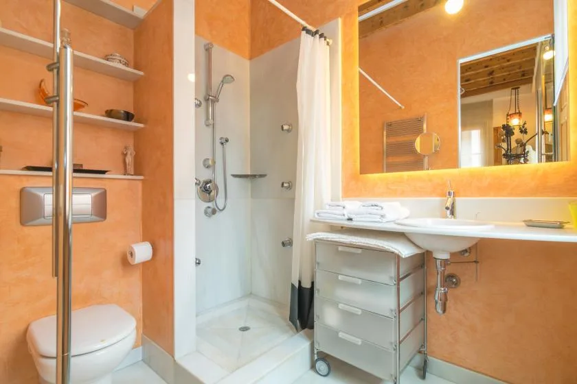 A bathroom with a shower, toilet, and sink beneath a large mirror.