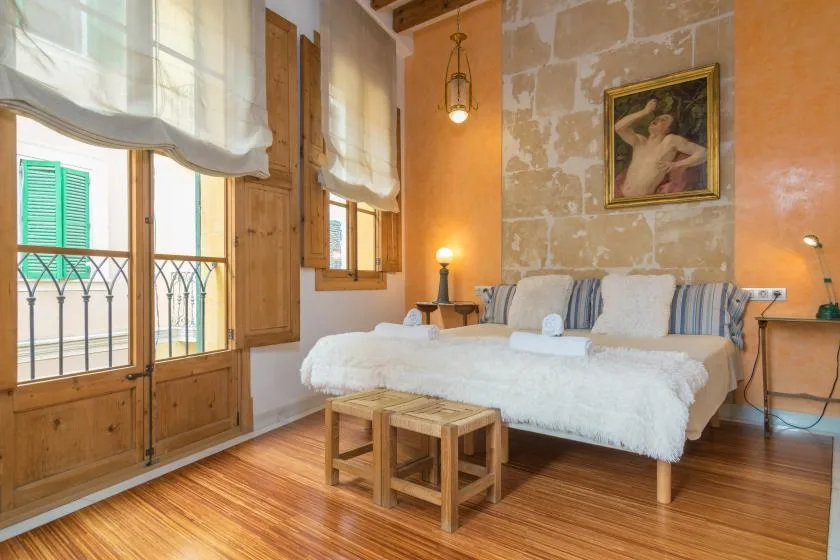 A bedroom with a bed, wooden shutters, and tall windows.