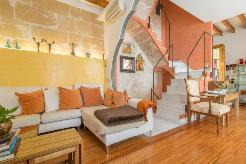 Una sala de estar y comedor con asientos, una escalera y suelo de madera.