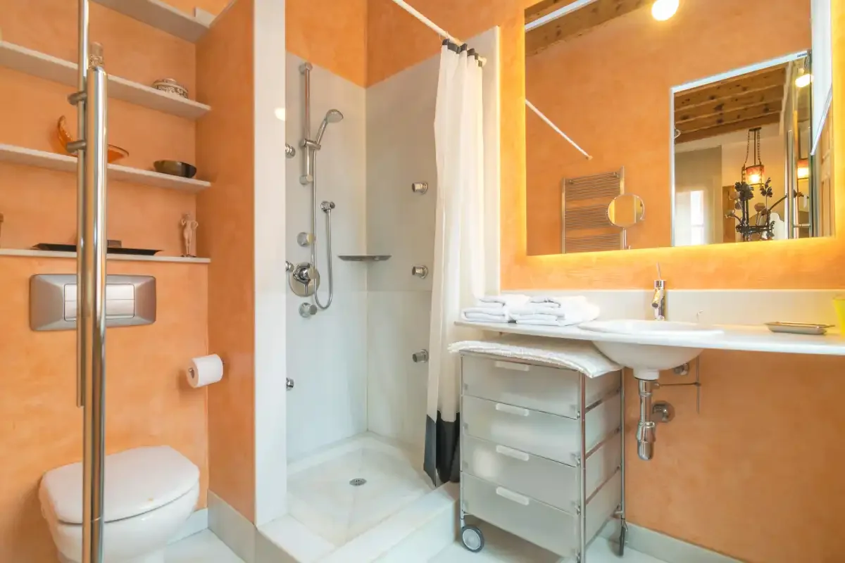 A bathroom with a shower, toilet, and sink beneath a large mirror.