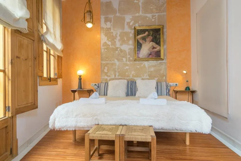 A bedroom with a large bed, wooden shutters, and a framed picture on the wall.