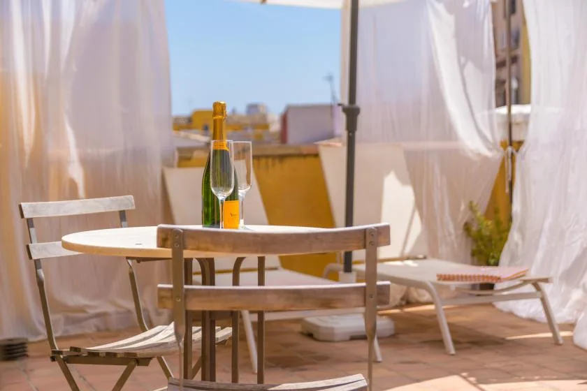 A sunlit outdoor seating area with sheer curtains and a small table.