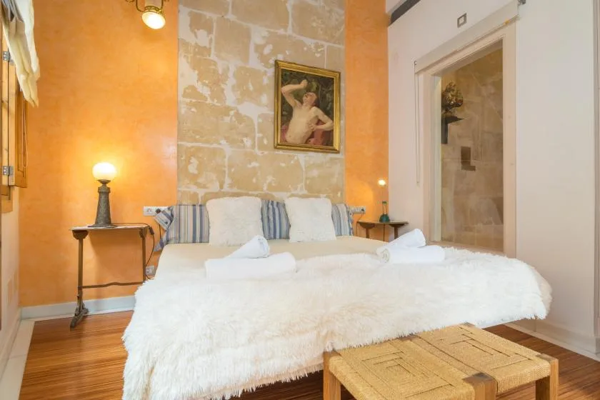 A bedroom with a large bed, white bedding, and warm orange walls.