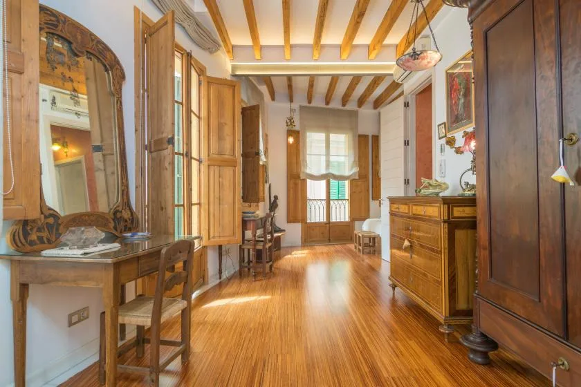 A wood-furnished room with exposed ceiling beams and a bright window at the far end.