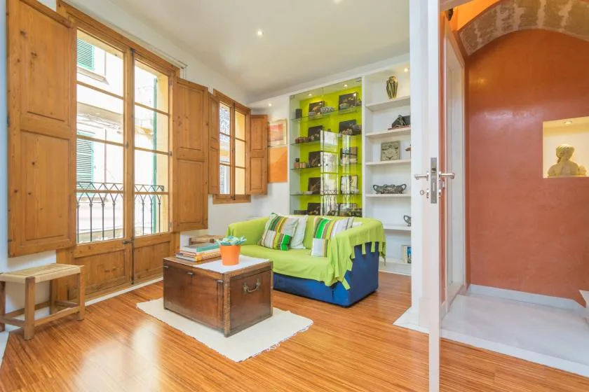 Living room with a bright green sofa beside tall windows.