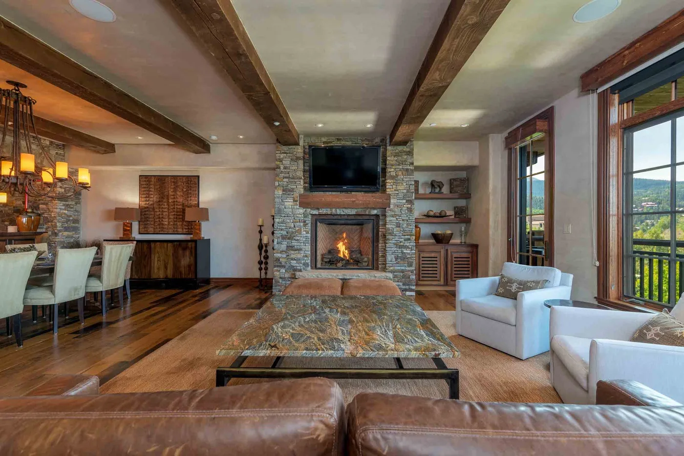 A living room with a stone fireplace and seating around a coffee table.