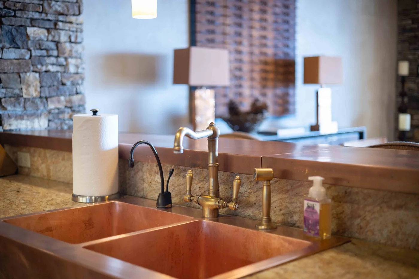 A bathroom vanity with a double sink, brass faucets, and a large mirror.