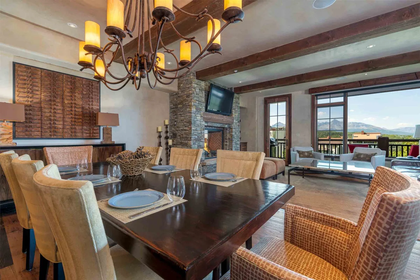 A dining area with a large wooden table beside doors opening onto a balcony.