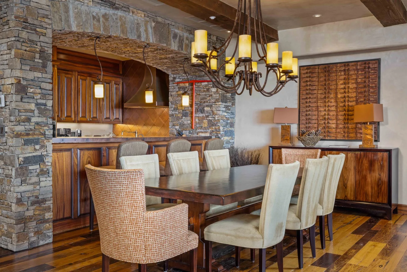 A dining area with a wooden table and chairs beside a stone-accented kitchen.