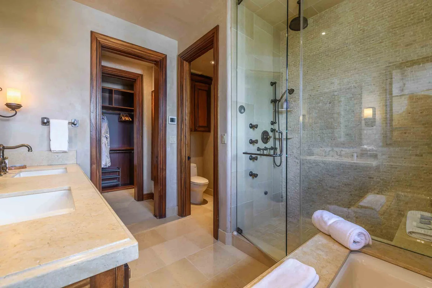A bathroom with a glass shower, vanity, and an open doorway.