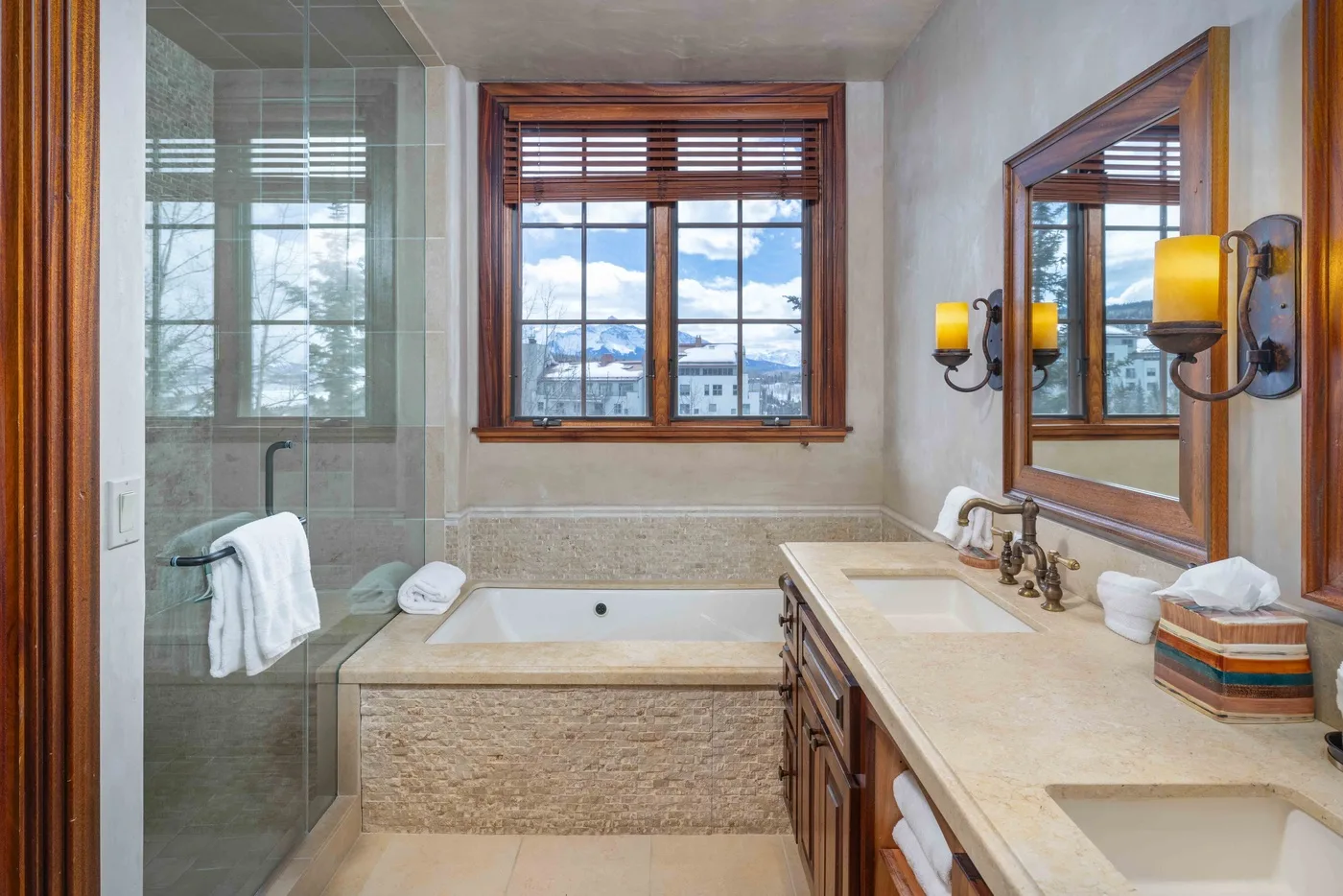 A bathroom with a bathtub, glass shower, and vanity beneath a window.