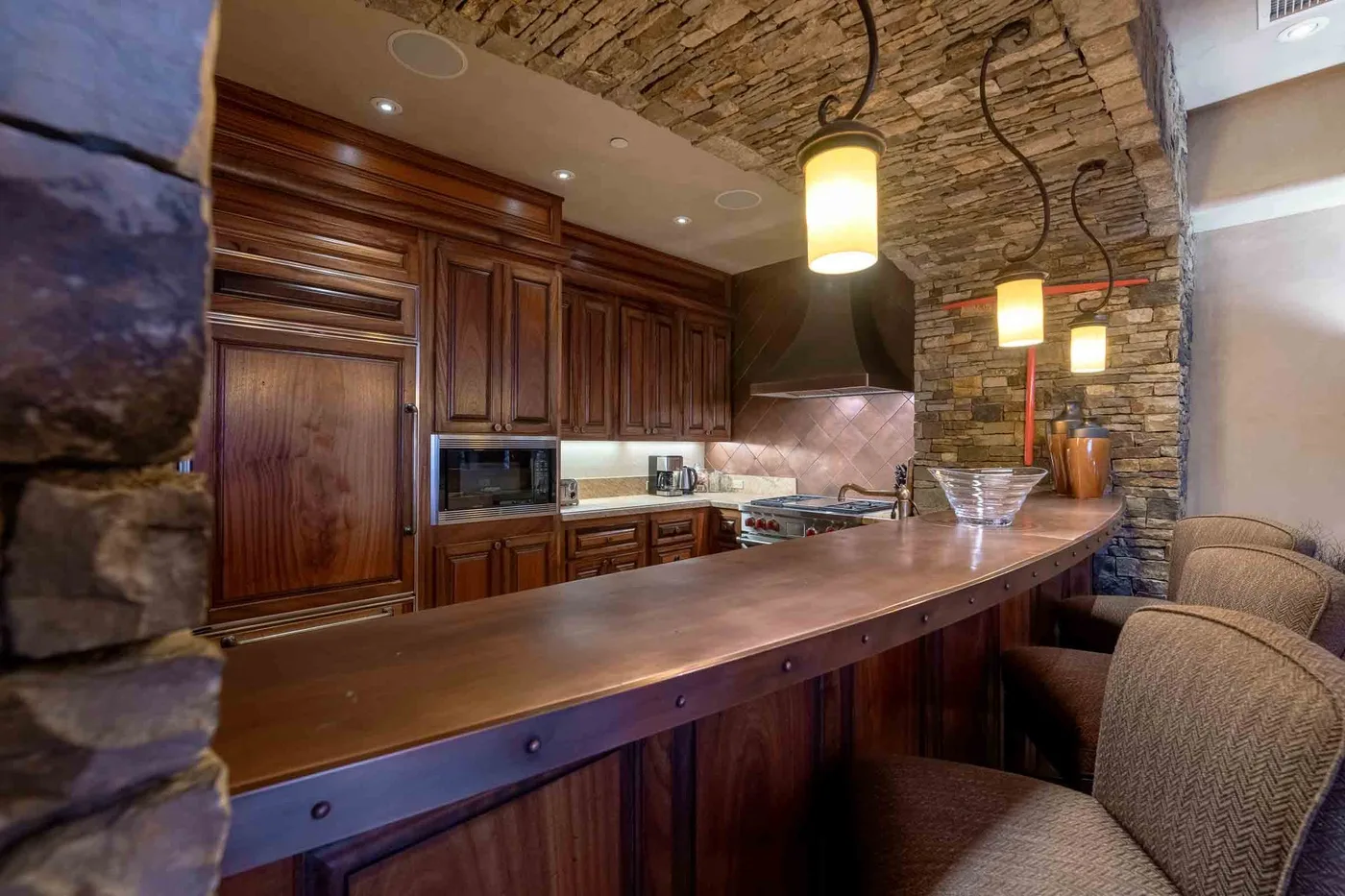 A rustic kitchen bar with dark wood cabinets and warm pendant lighting.