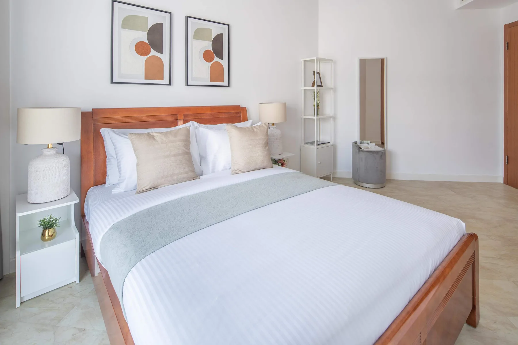 Un dormitorio luminoso con una cama de madera vestida con ropa de cama blanca.