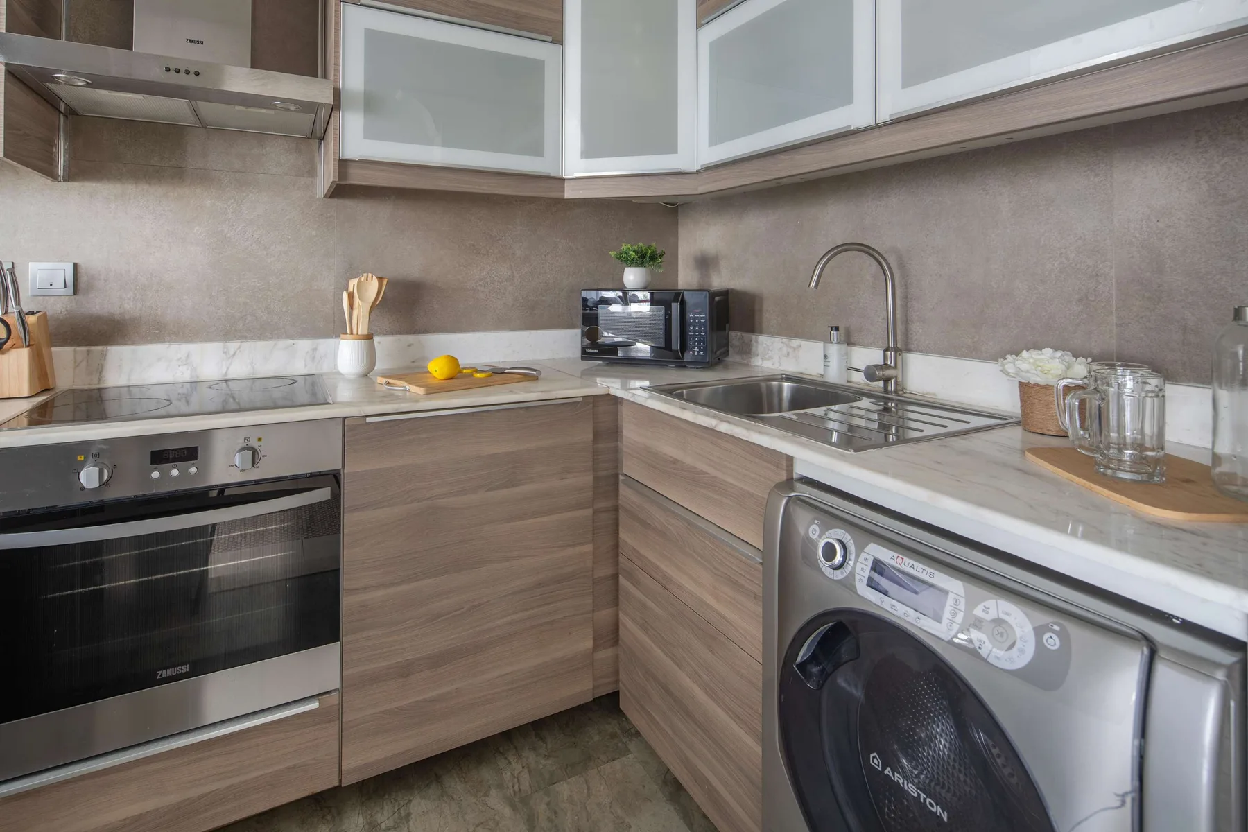 Una cocina compacta con armarios de madera, electrodomésticos de encimera y un fregadero.