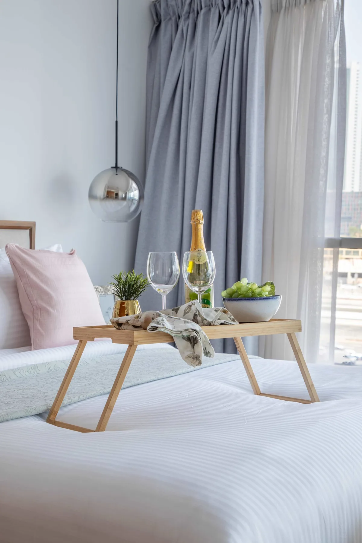 Una zona de estar en un dormitorio, con una mesa baja de madera junto a cortinas largas.