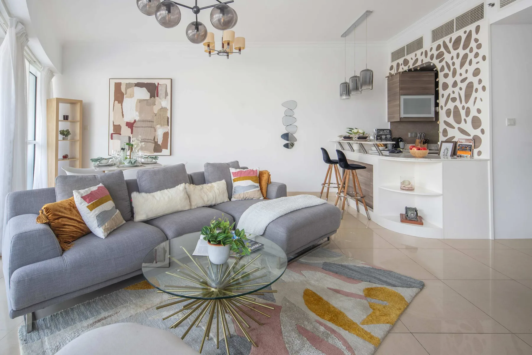 Una sala luminosa con asientos grises y una cocina abierta.