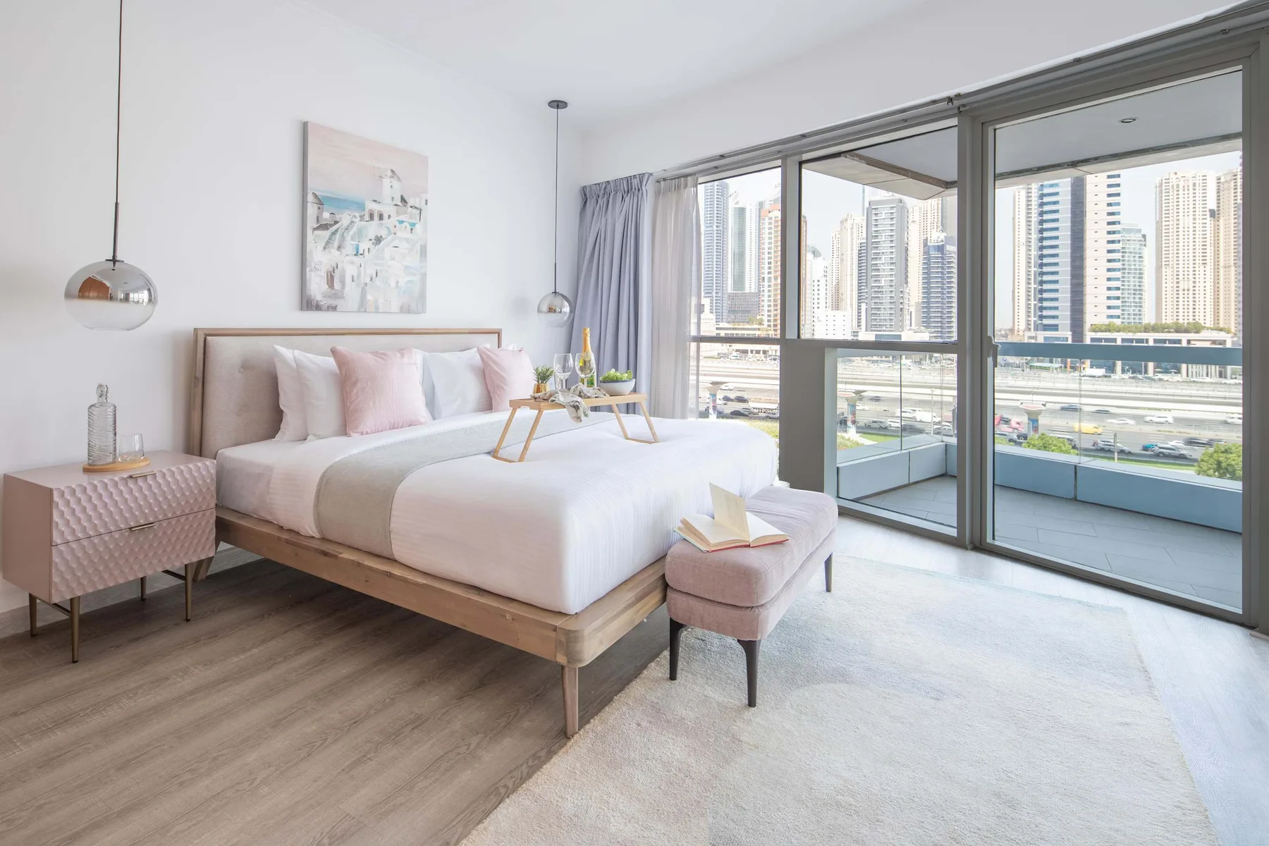 Un dormitorio luminoso con una cama bien arreglada junto a ventanales.