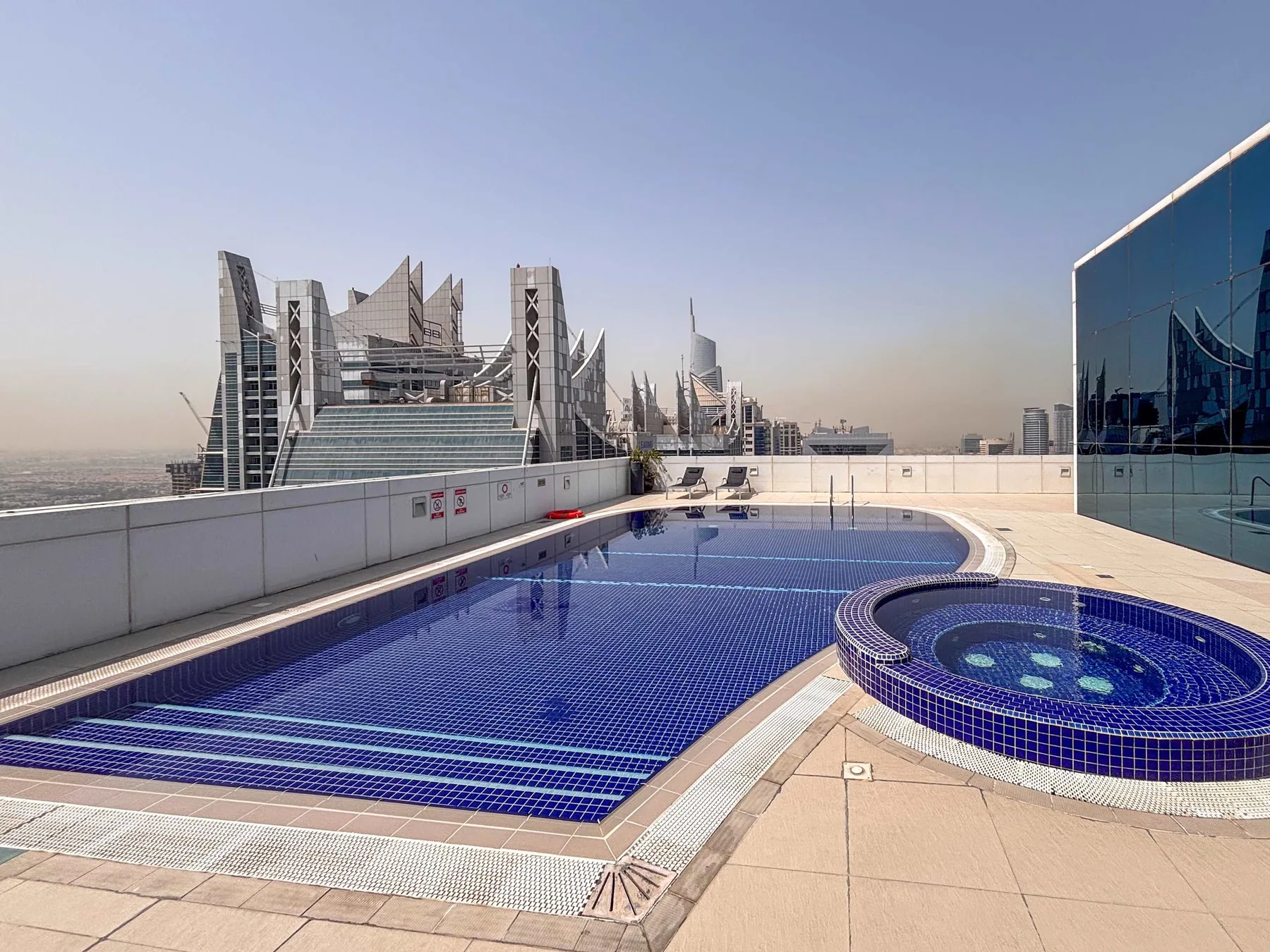 Una piscina en la azotea y un spa circular se encuentran junto al horizonte urbano.