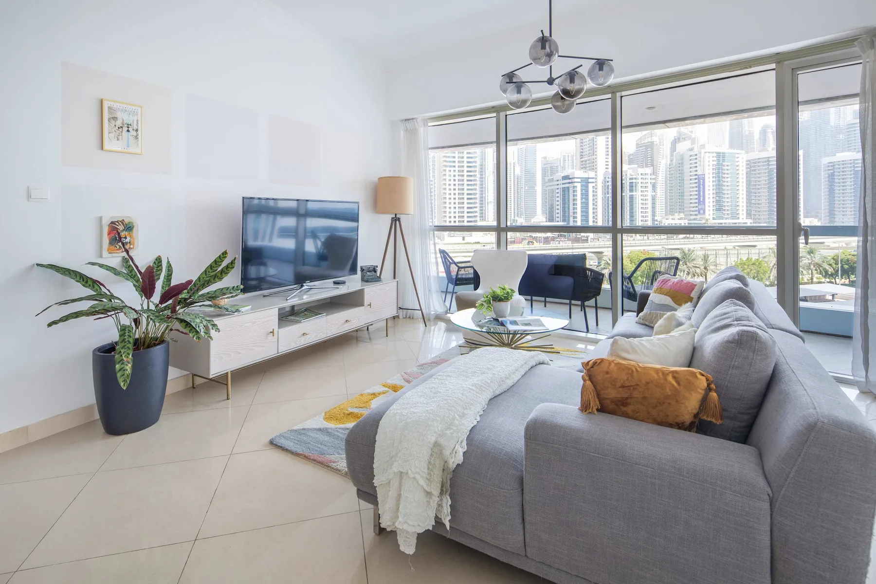 Una sala luminosa con asientos grises y grandes ventanales con vistas a edificios de la ciudad.