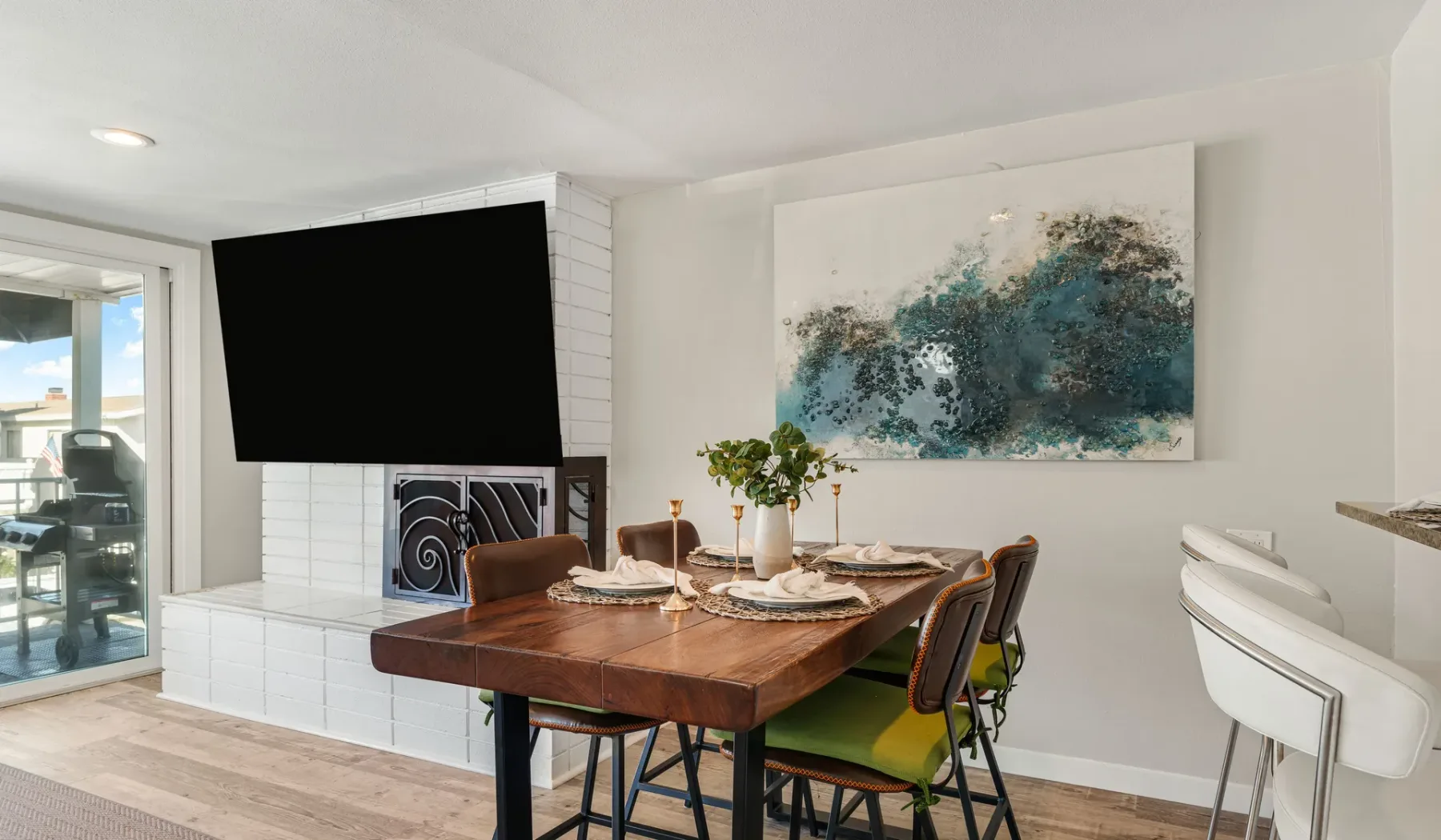 Comedor con una mesa de madera, sillas y un gran cuadro abstracto.