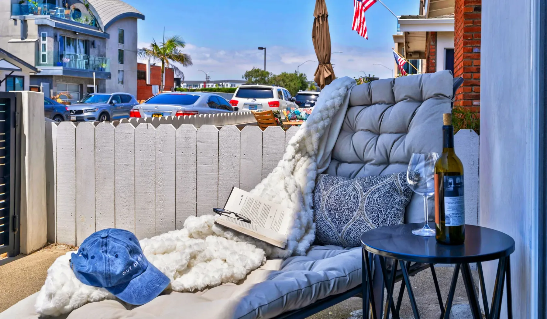 Una zona de estar al aire libre con un sillón acolchado y una mesa junto a una cerca.