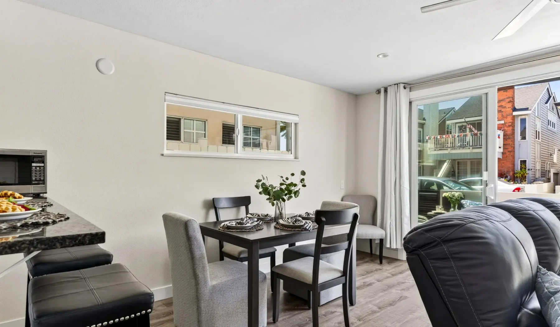 Una luminosa zona de comedor y sala de estar con una mesa junto a grandes ventanas.