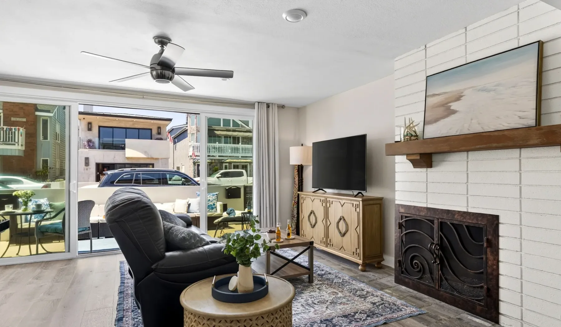 Una sala de estar con asientos, un televisor y una chimenea junto a grandes ventanas.