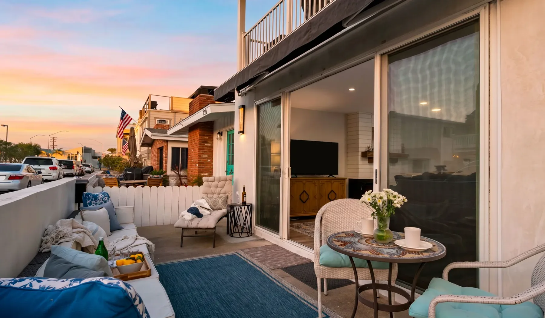 Un patio amueblado con asientos y puertas corredizas de vidrio al atardecer.
