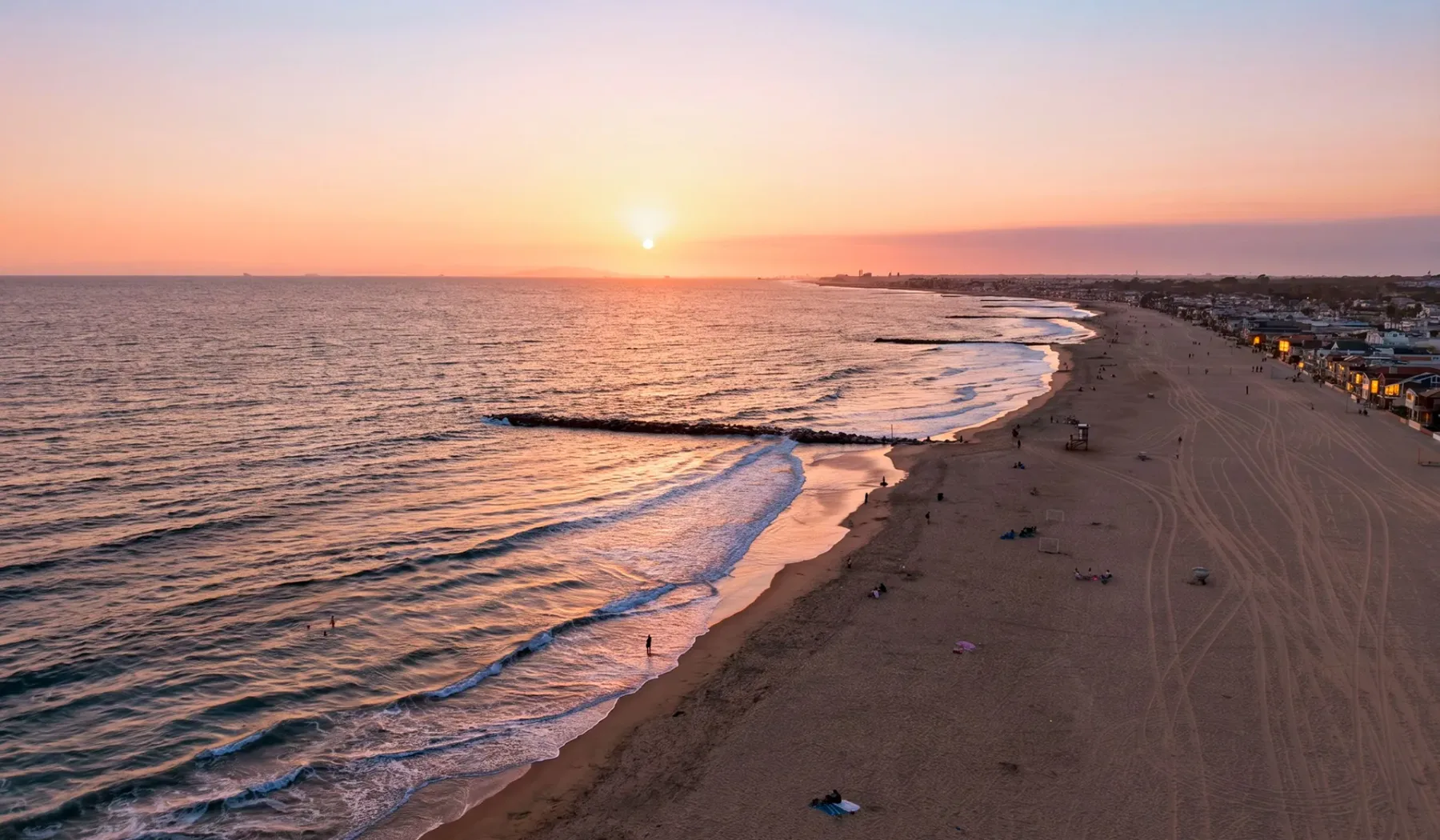 Una playa de arena se curva junto al mar bajo el sol poniente.