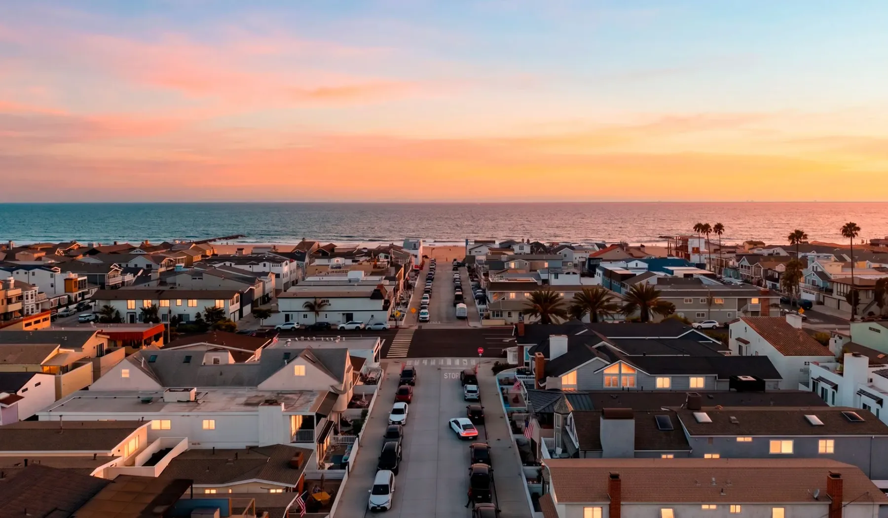 Un vecindario costero al atardecer, con casas a lo largo de una calle junto al océano.