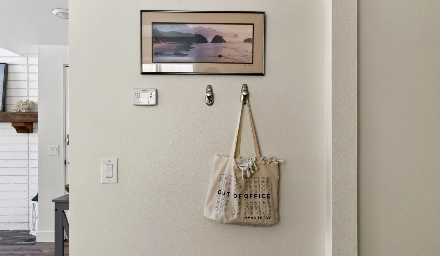 Una pared de pasillo muestra una obra enmarcada y una bolsa de lona colgada.